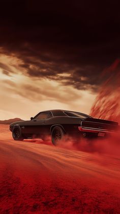 a black car driving down a dirt road under a cloudy sky with red dust behind it