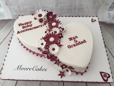 two heart shaped cakes with happy anniversary written on the top and flowers in the middle