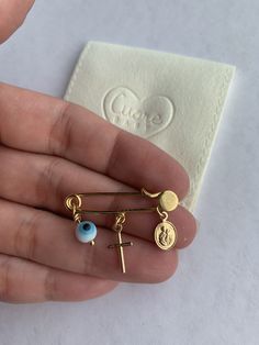 a person is holding three different types of earring sets in their hand, one with an eyeball and the other with a cross on it