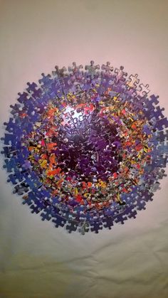 a purple and blue circular puzzle on a white surface with lots of small pieces scattered around it