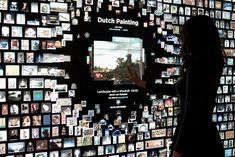 a woman standing in front of a wall full of pictures