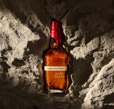 a bottle of liquor sitting on top of a rocky hill next to a red cap