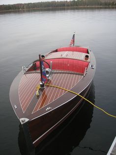 a wooden boat tied to the dock with an american flag on it's bow