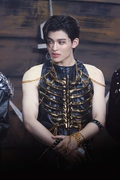 a man in black leather with gold chains on his chest