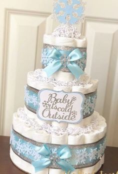 a three tiered diaper cake decorated with snowflakes and blue ribbon bows