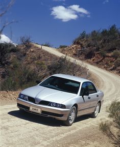 a silver car parked on the side of a dirt road