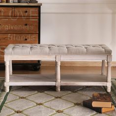 a white bench sitting on top of a rug in front of a dresser and drawers