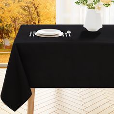 a black table cloth with white plates and utensils on it in front of a window