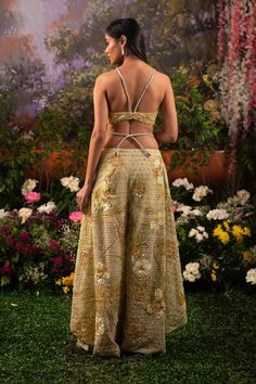 Behold the modern royalty through this Alana co-ord set. The ensemble comprises a bralette blouse paired with unconventional wide-legged pants and a heavily embellished cape. The monochrome outfit is highlighted with shiny sequins and beads crafting motifs of flowers and birds resonating a heavenly garden. Deep v-neck bralette attached with rhinestone embellished straps. The hook is attached to the back side of the blouse. Unconventional wide-legged pants with attached rhinestone straps at the w Evening Party Wear Sets With Cape Sleeves, Evening Sets With Cape Sleeves For Party Wear, Party Wear Sets With Cape Sleeves For Evening, Floor-length Embellished Palazzo Set For Evening, Chic Festive Evening Pant Set, Chic Evening Festive Pant Set, Hand Embellished Floor-length Evening Sets, Hand Embellished Evening Sets In Floor-length, Glamorous Floor-length Evening Sharara