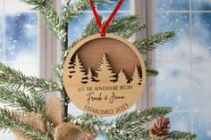 a wooden ornament hanging from a christmas tree with pine trees in the background