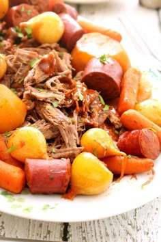 a white plate topped with meat, potatoes and carrots on top of a wooden table