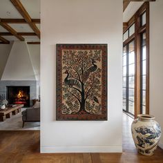 a painting hanging on the wall next to a large vase and fire place in a living room