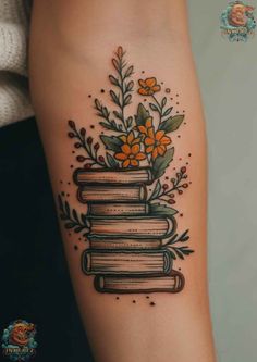 a tattoo with books and flowers on it