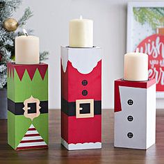 three boxes with candles in them sitting on a table next to a christmas card box