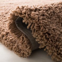 a close up view of a brown rug on the floor with it's edge partially covered