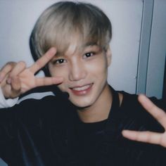 a young man making the peace sign with his hand while wearing a black t - shirt