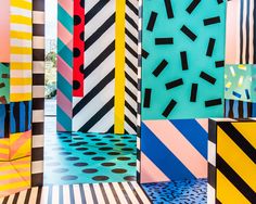 an array of colorful art pieces on display in a room with black and white stripes