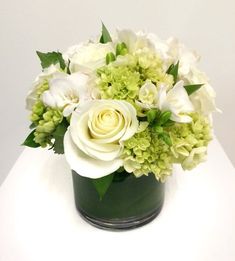 a green vase filled with white flowers on top of a table