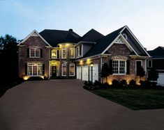 a large brick house lit up at night with lights on the front and side windows