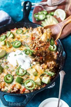 a skillet filled with mexican casserole and topped with sour cream, jalapenos