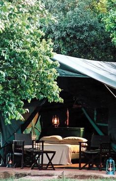 a tent set up in the woods with tables and chairs