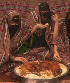 three people in black face masks sitting on a couch eating food from a pancake