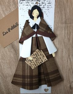 a paper doll made to look like a woman in brown and white dress with black hair