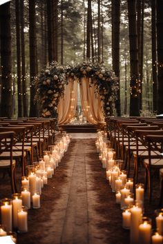 an outdoor wedding setup with candles and flowers on the aisle, surrounded by tall trees