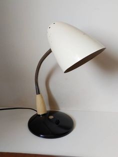 a white desk lamp sitting on top of a table next to a black light bulb