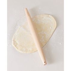 an uncooked pizza dough with a wooden rolling pin on the side, ready to go into the oven