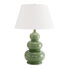 a green lamp sitting on top of a table next to a white lampshade