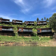 several houses on the side of a hill near water