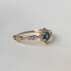 a gold ring with blue and white stones on it's side, sitting on a table