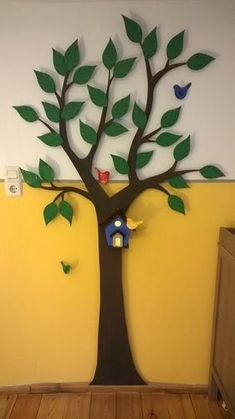 a tree with green leaves and birds on it in front of a wall mounted light switch