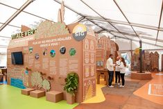 people are standing in front of a cardboard structure with trees on it and information about the environment