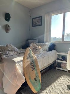 a bedroom with a surfboard on the bed and other items in the window sill