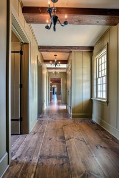 an empty hallway with wood flooring and ceiling lights on either side of the hall