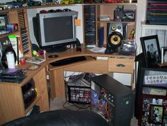 a computer desk with a monitor and speakers on it in a room full of other items