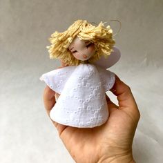 a hand holding a small white angel figurine