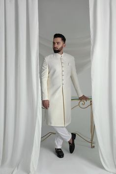 This White Long Sherwani is a stunning choice for your special occasion. Made from printed off-white khaadi silk, it features a silk kurta and cotton pajama for a comfortable fit. Complete your look with the elegant organza Rajastjhani kula (turban) and exude an air of style and sophistication. Elegant Cotton Silk Kurta With Cutdana, Cream Cotton Silk Kurta With Traditional Drape, Cream Cotton Silk Traditional Wear For Wedding, Cotton Silk Nehru Jacket For Wedding Long Sleeve, Long Sleeve Cotton Silk Nehru Jacket For Wedding, Designer Off-white Bandhgala For Eid, Fitted White Cotton Silk Kurta, White Fitted Cotton Silk Kurta, Elegant Cream Cotton Silk Traditional Wear