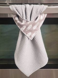 a white towel hanging from the side of an oven door, with a silver and white design on it