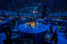 a room filled with lots of tables covered in blue cloths and lit up candles