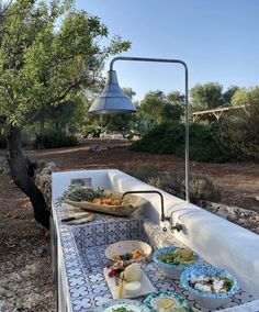 an outdoor table with food on it and a bell hanging from the ceiling in the background