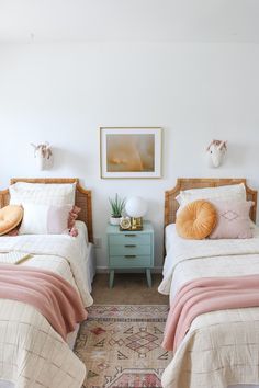 two twin beds in a white bedroom with pink and orange pillows