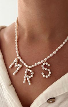 a woman wearing a necklace with pearls on it