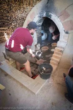 two men are working in an outdoor oven