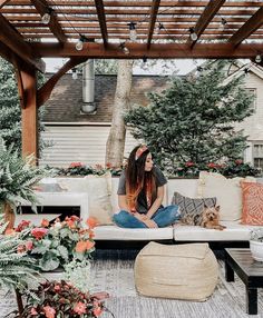 a woman sitting on top of a white couch next to a wooden pergoline