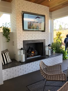 a living room with a fire place sitting under a flat screen tv on top of a brick wall