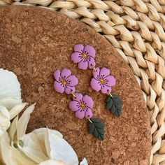 three purple flowers are sitting on top of a cork board next to some white flowers