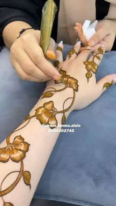 a woman is doing hendi on her arm with flowers and leaves painted on it